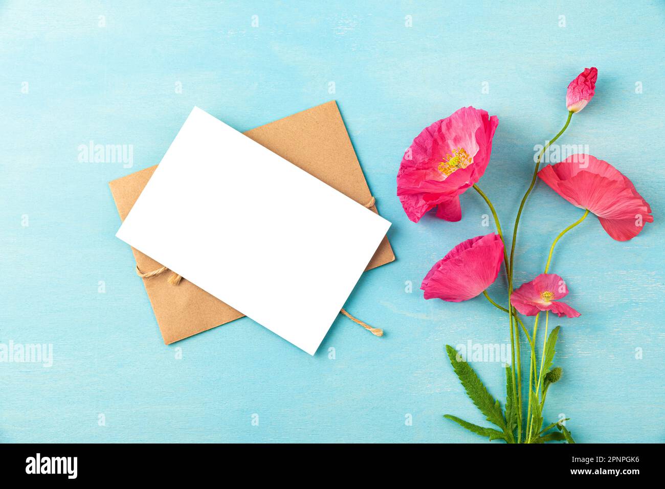 Carte de vœux vierge avec bouquet de fleurs de pavot rose sur fond bleu pastel. Invitation de mariage. Maquette. Pose à plat. Vue de dessus Banque D'Images