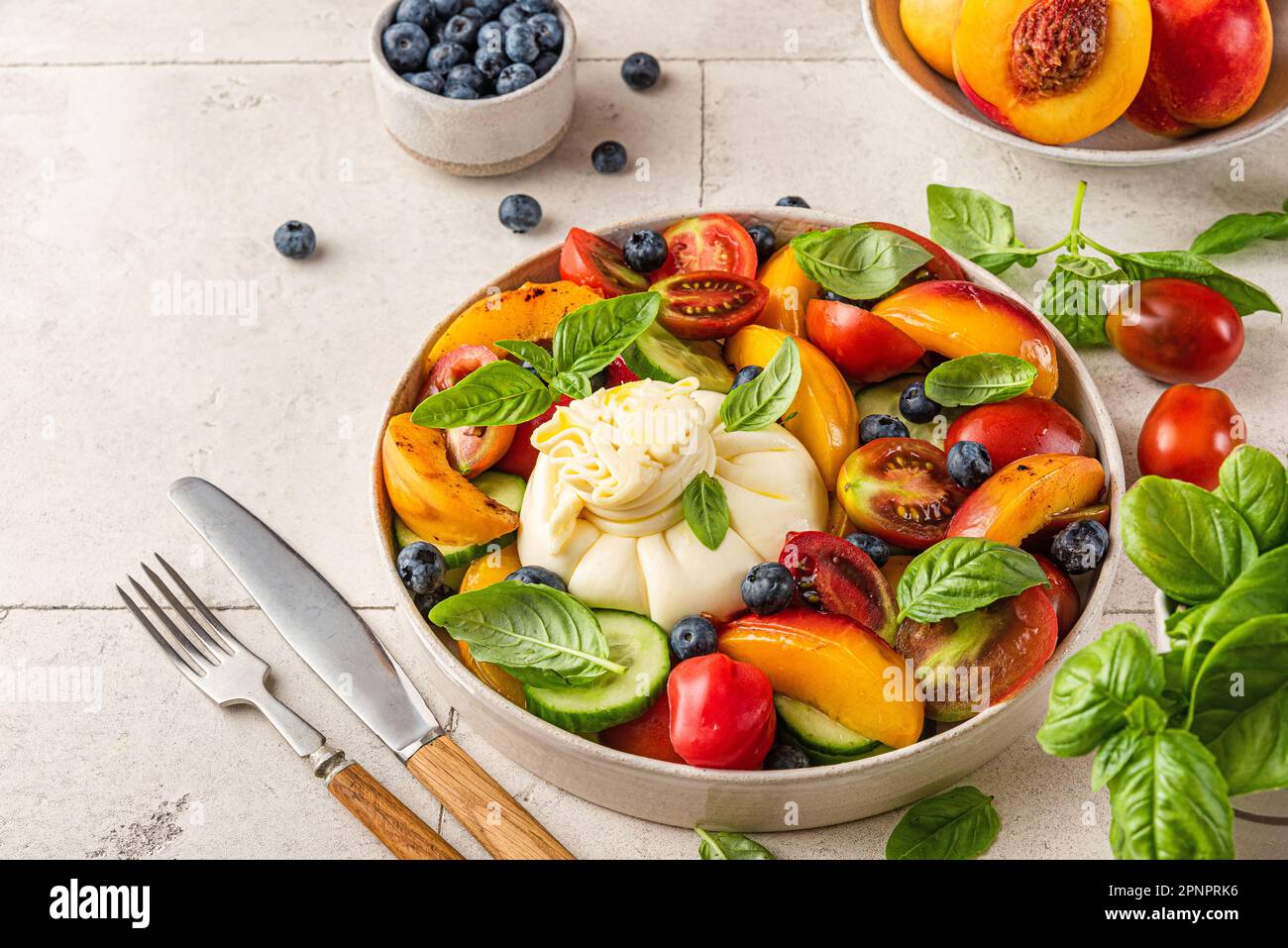 Salade de fruits et légumes d'été avec fromage burrata et basilic dans ...