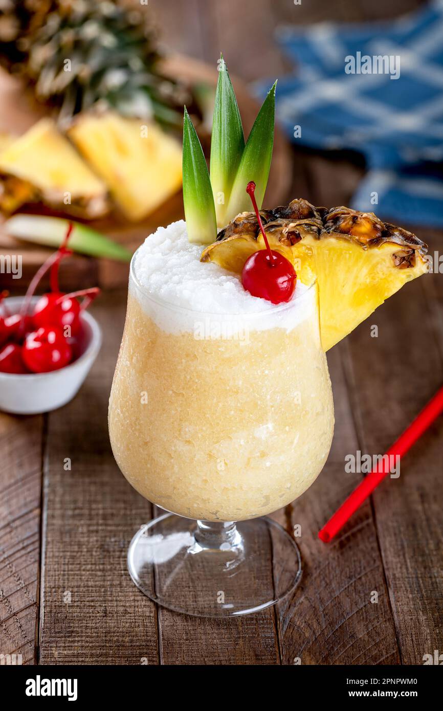 Cocktail Pina colada avec cerise, tranche d'ananas et feuilles sur une table rustique en bois Banque D'Images