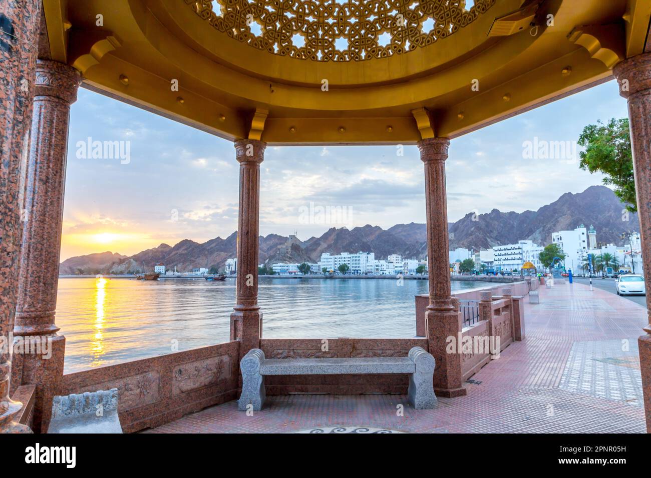 Bâtiments le long de la promenade en bord de mer avec toile de fond de montagne au lever du soleil, Muscat, Oman Banque D'Images