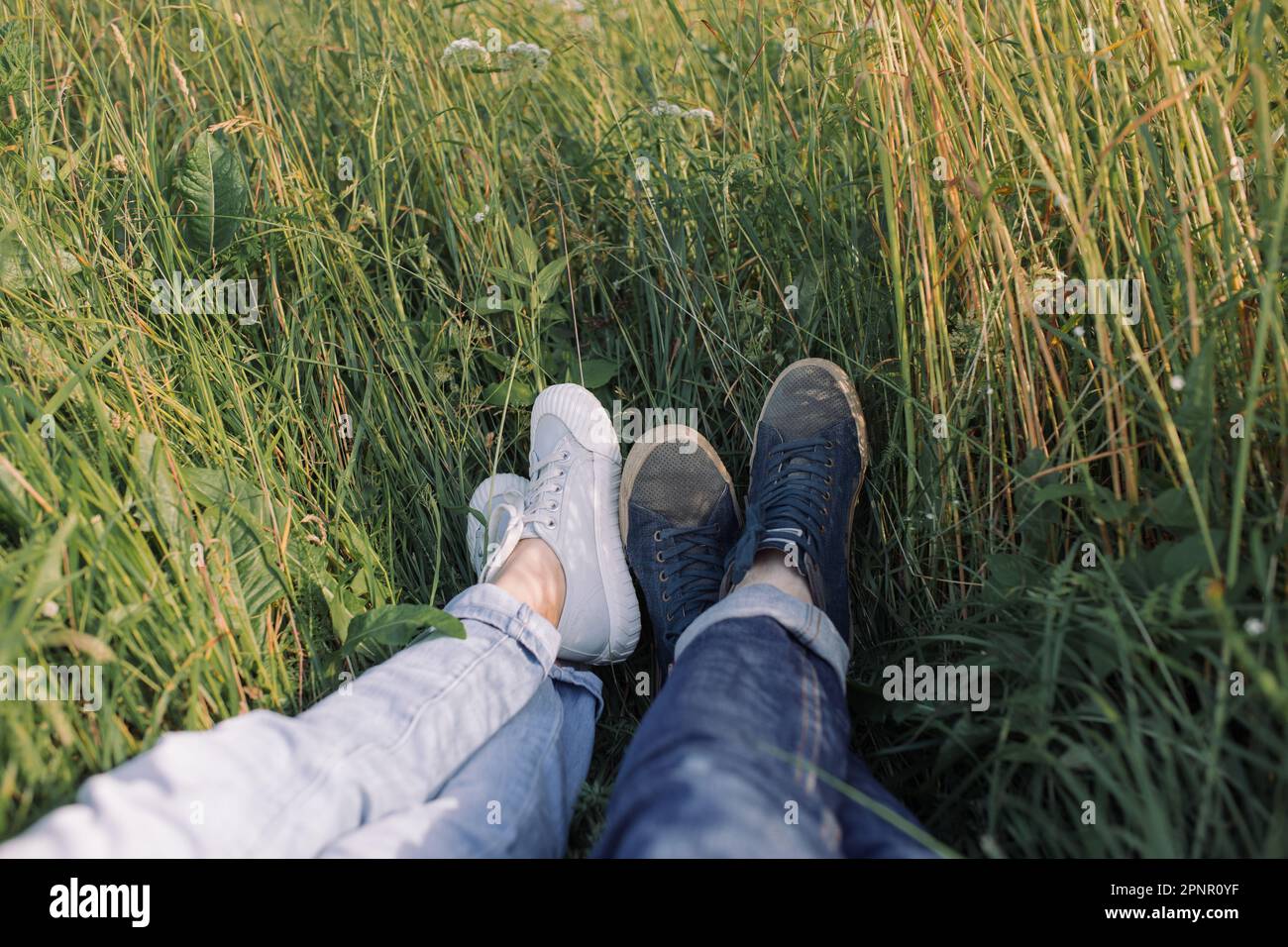 Gros plan des jambes d'une jeune femme et d'un homme couché dans un champ en été, Biélorussie Banque D'Images