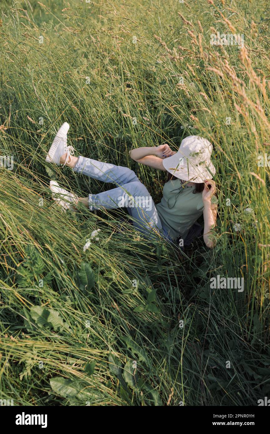 Femme couchée dans une herbe longue dans un pré d'été, Biélorussie Banque D'Images