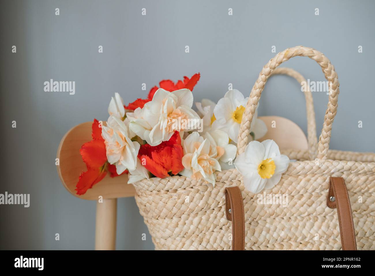 Jonquilles et tulipes dans un panier de paille sur une chaise Banque D'Images