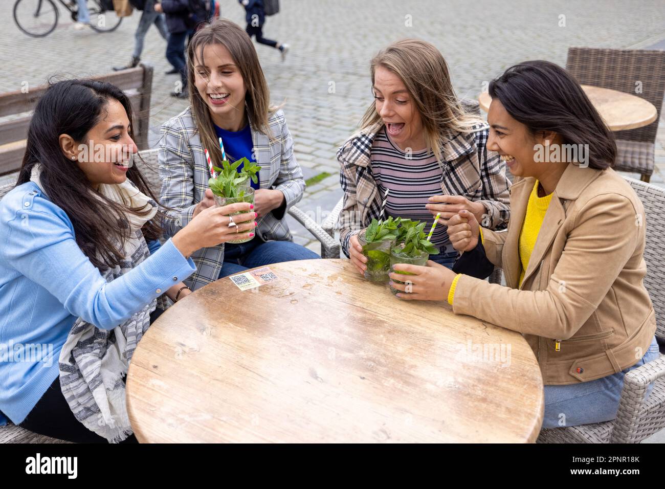 21 mai 2021, Anvers, Belgique, quatre jeunes femmes de course mixte qui toastent avec un cocktail en plein air dans le centre-ville après la réouverture des bars fermés pour des restrictions de corona ou Covid-19.Photo de haute qualité Banque D'Images