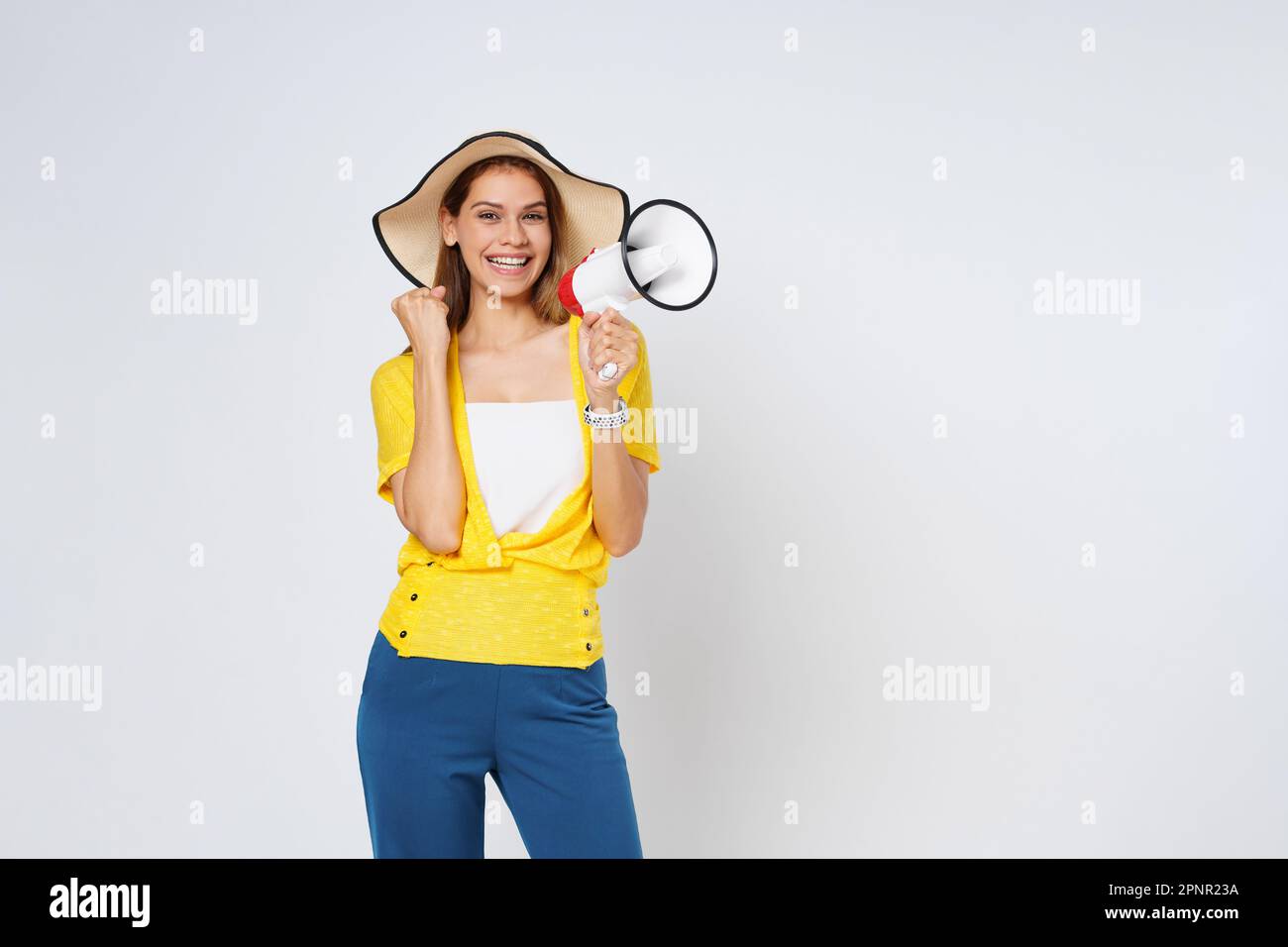 Jeune femme portant un chapeau de soleil et tenant le mégaphone isolé sur fond blanc. Style de vie été et annoncer le concept. Banque D'Images