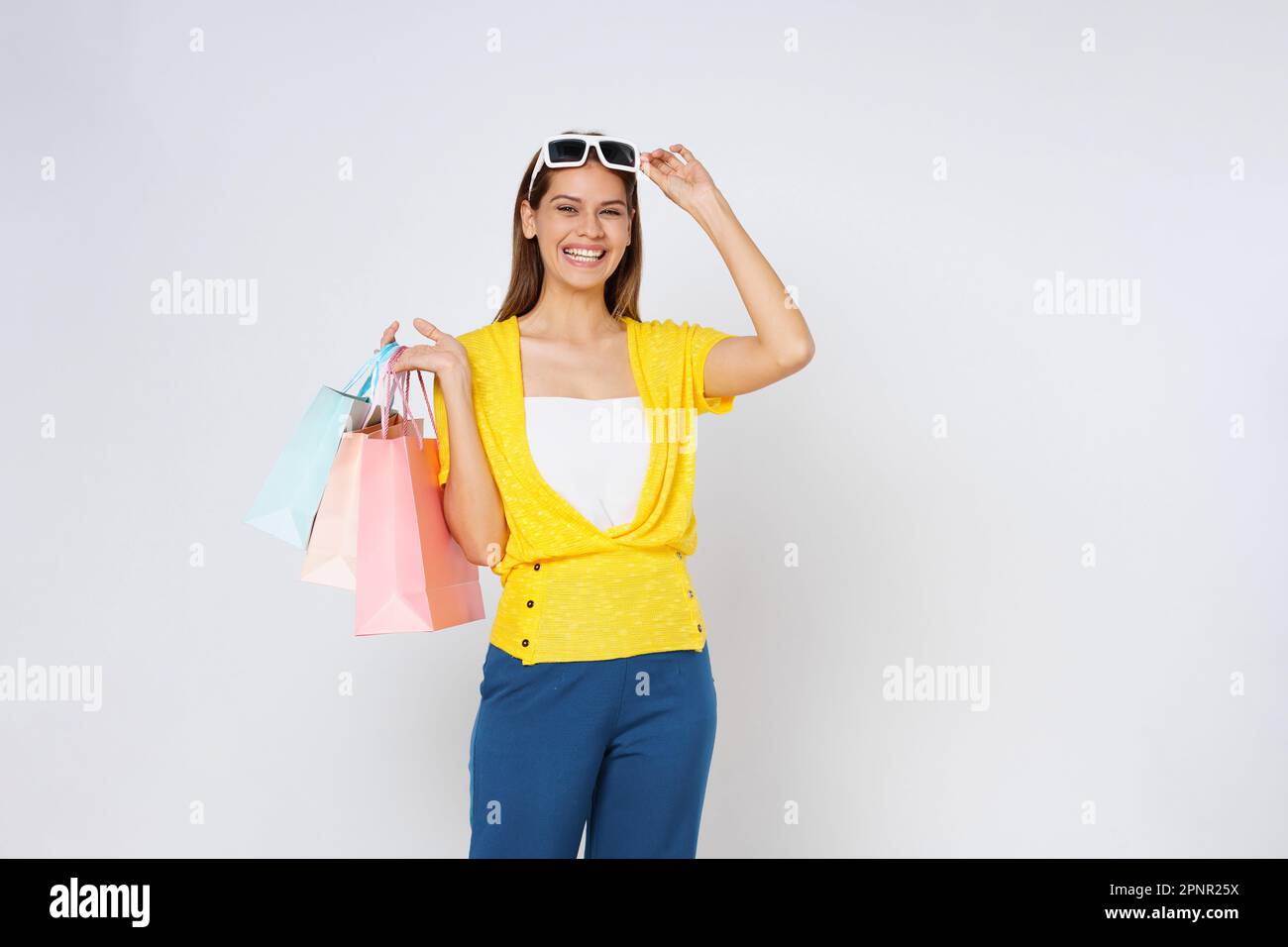 Portrait d'une jeune femme émotive excitée portant et touchant des lunettes de soleil tenant des sacs de shopping colorés isolés sur fond blanc. Banque D'Images