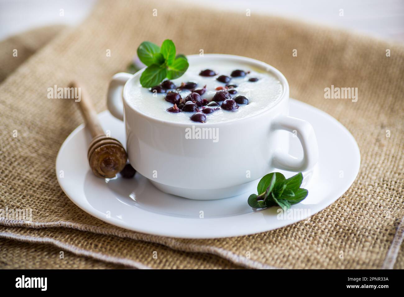 Porridge de semoule de lait cuit avec baies et miel dans une assiette, sur une table en bois. Banque D'Images