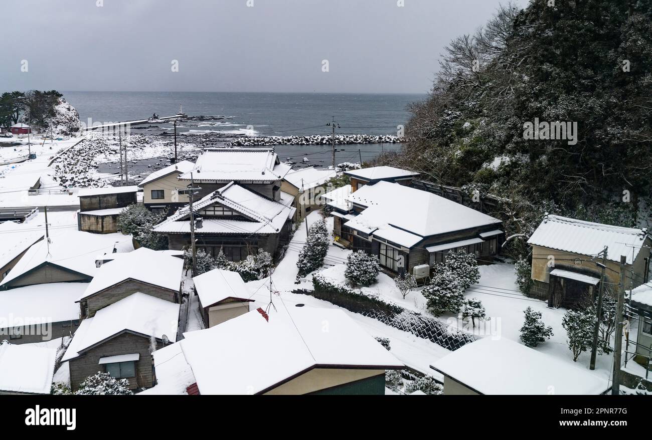 Un village en hiver sur la côte de la mer du Japon dans la préfecture d'Aomori, vu à partir d'un train sur la ligne Gono. Banque D'Images