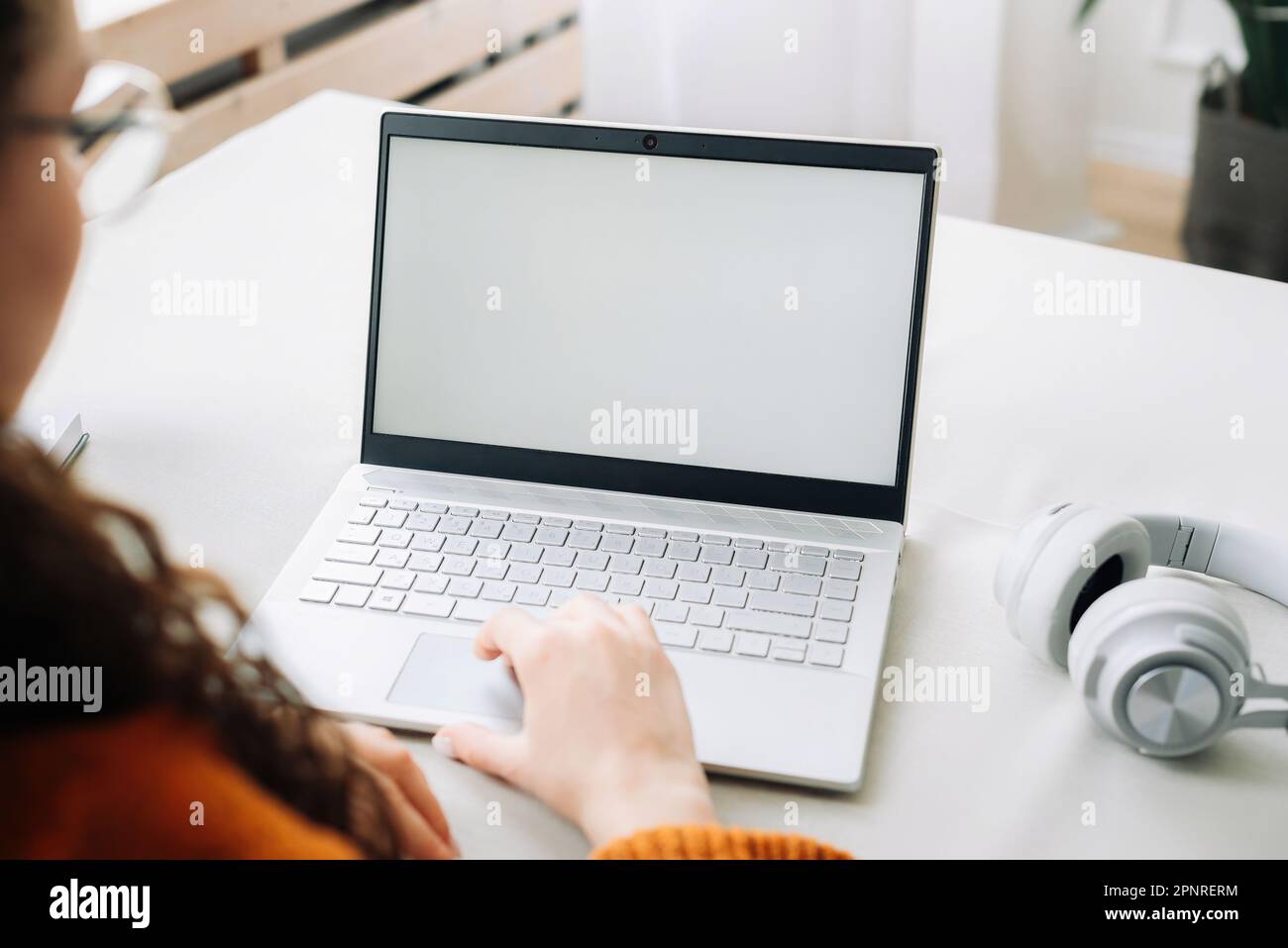 Vue sur l'épaule d'une femme étudiant en ligne regardant la maquette blanche écran vide en utilisant l'ordinateur portable apprentissage en ligne, le concept de travail à distance Banque D'Images