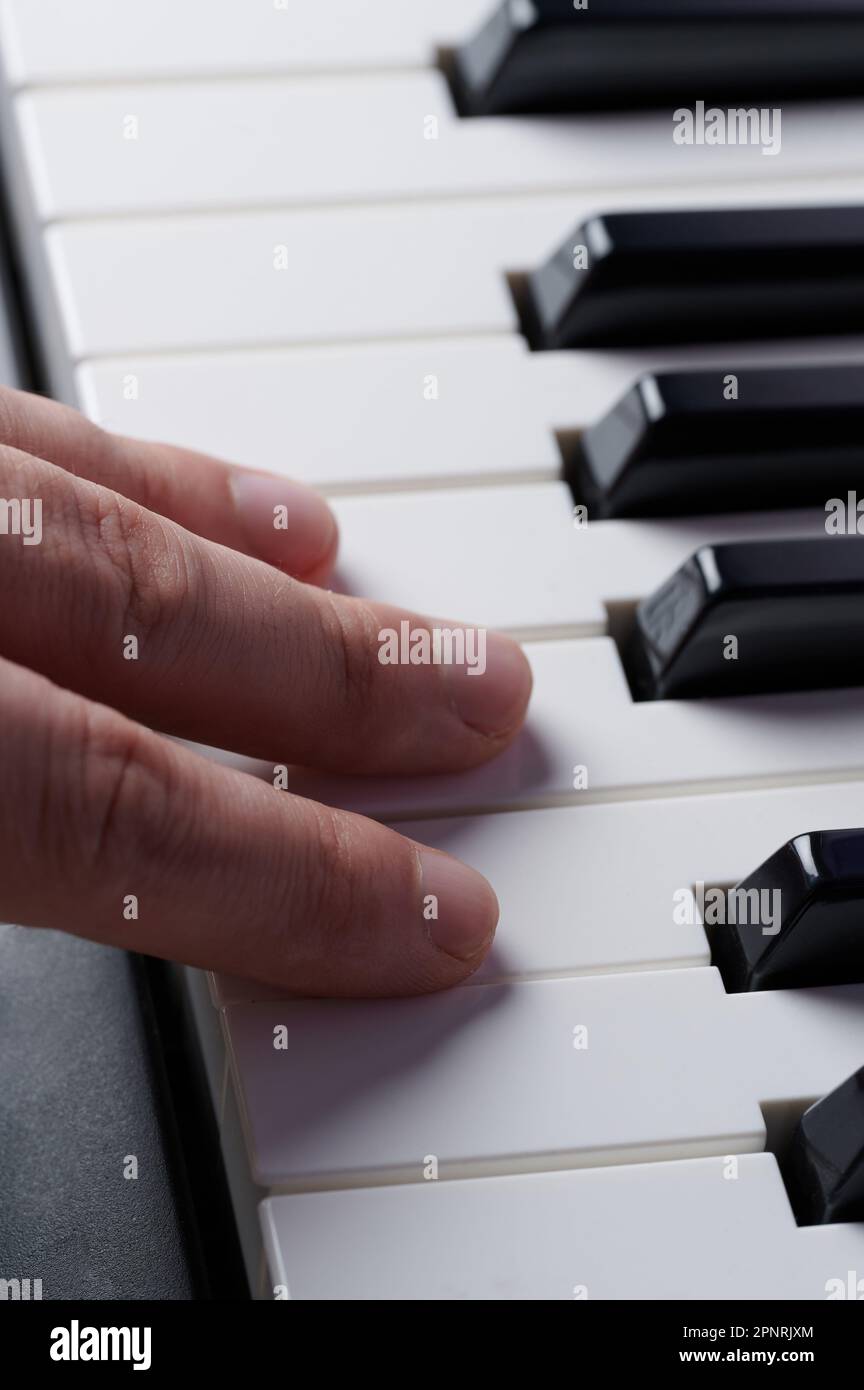 Vue rapprochée macro avec trois doigts sur les touches du piano Banque D'Images