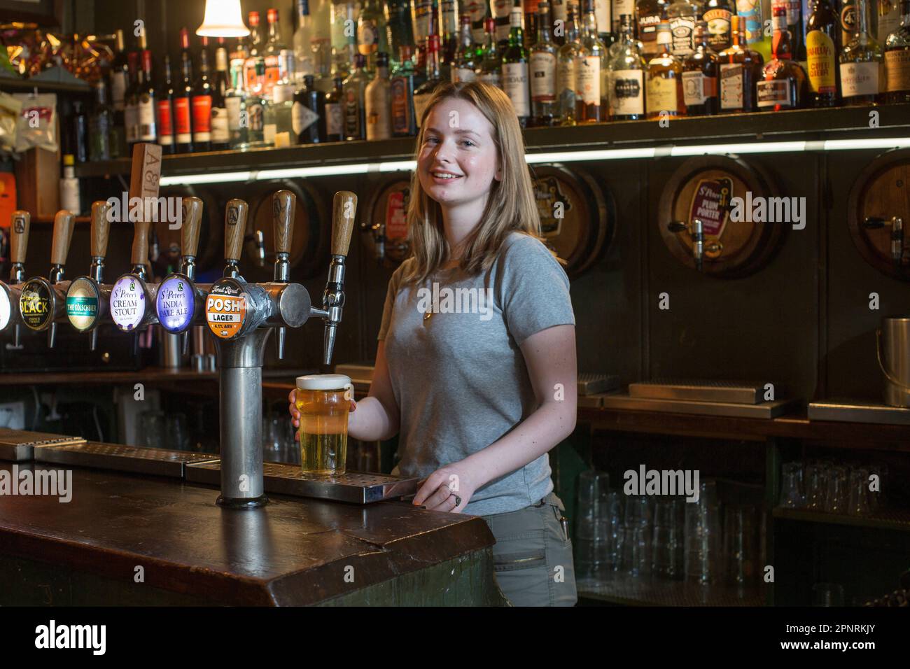 Pub barmaid versant une pinte de bière dans le pub, The Holy Tavern, dans Britton Street, Clerkenwell, Londres, Angleterre, Royaume-Uni. Banque D'Images