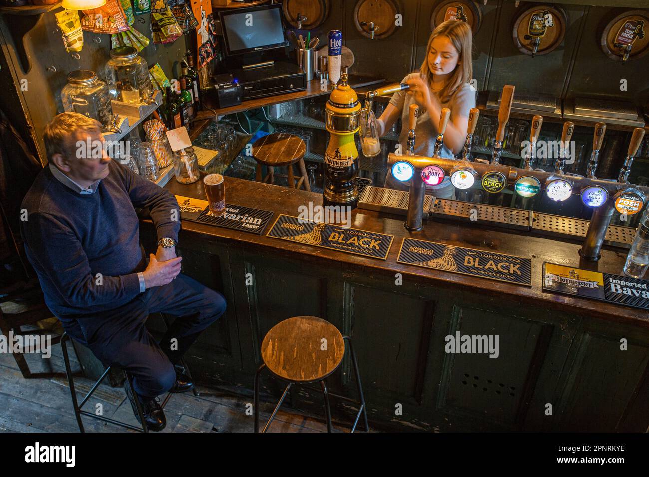 Pub barmaid versant une pinte de bière dans le pub, The Holy Tavern, dans Britton Street, Clerkenwell, Londres, Angleterre, Royaume-Uni. Banque D'Images