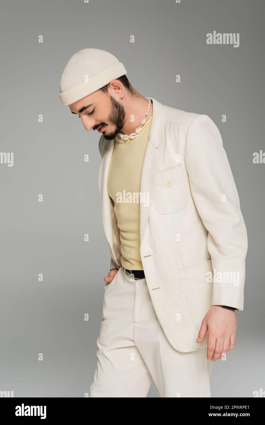 Homme homosexuel tendance en costume et chapeau posant isolé sur gris, image de stock Banque D'Images