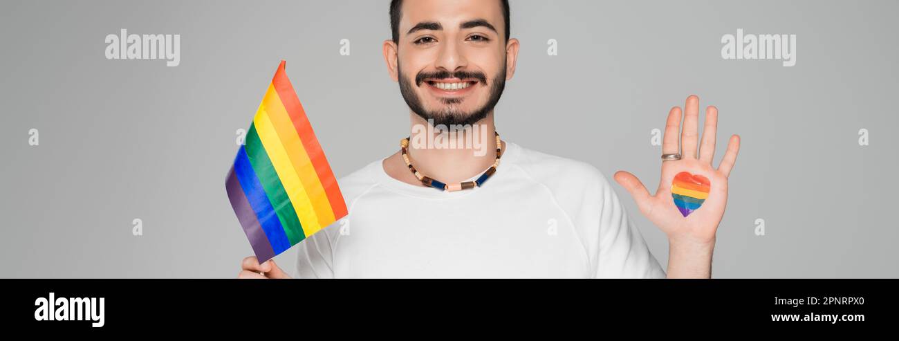 Homme homosexuel gai avec le drapeau lgbt et le coeur sur la main isolé sur gris, bannière, image de stock Banque D'Images