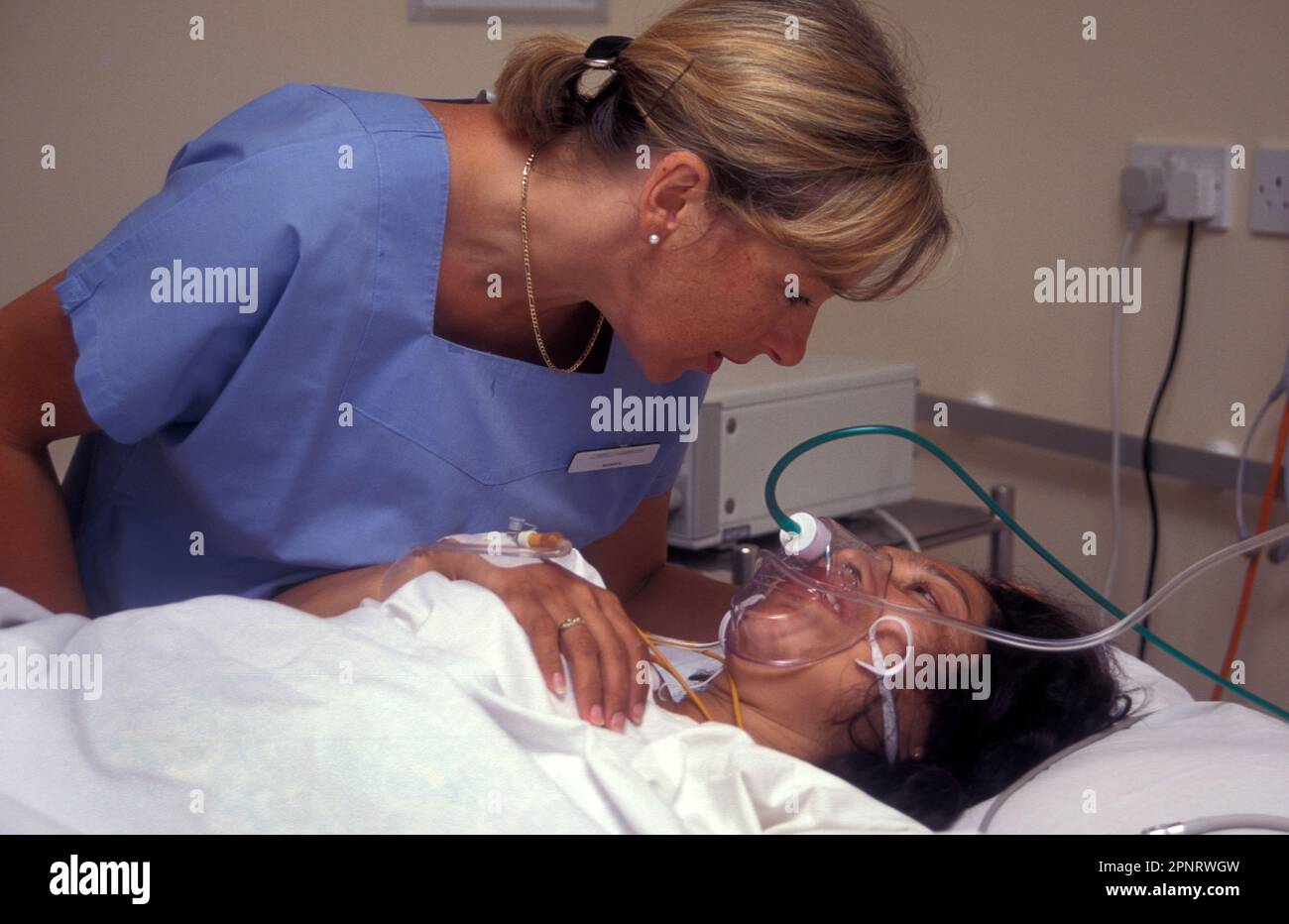 la sage-femme consolant la femme enceinte hispanique par des contractions intensives avec soulagement de douleur de gaz et d'air Banque D'Images