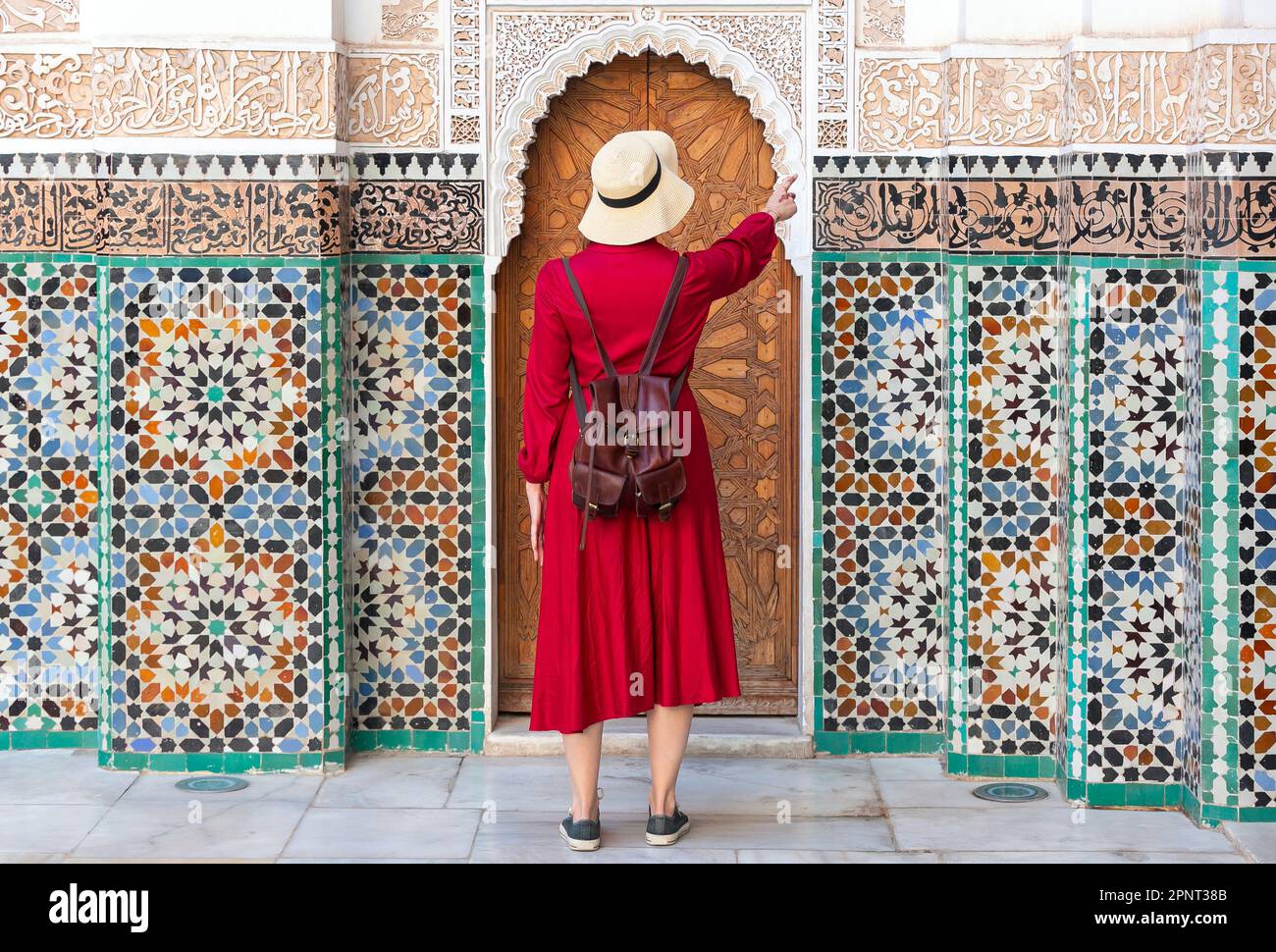 Jeune fille s'habiller en rouge avec un chapeau regardant le Ben Youssef Madrasa à marrakech, maroc Banque D'Images