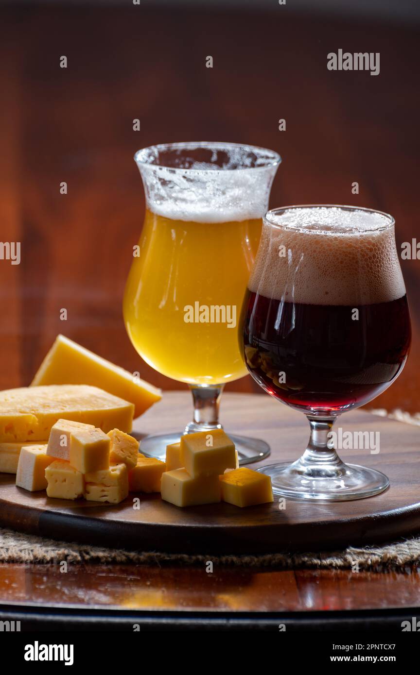 Verres de bière blonde jaune belge et brune foncée fabriqués en abbaye et en bois avec une variété de fromages belges, plats et bières assortis en Belgique Banque D'Images