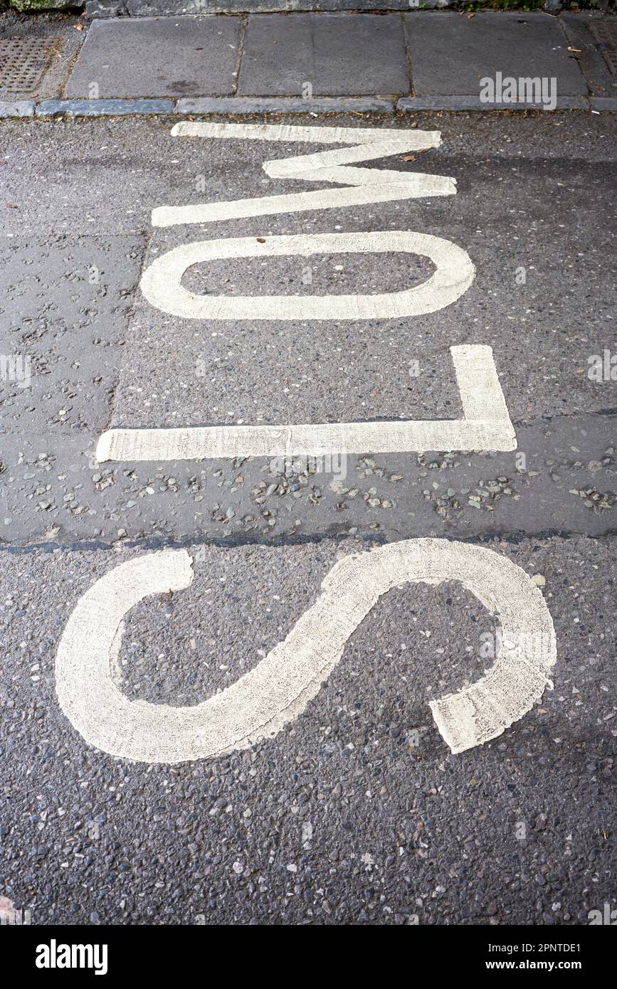 Le mot Slow en peinture blanche sur une surface de route en asphalte tarmac d'un angle inhabituel Banque D'Images