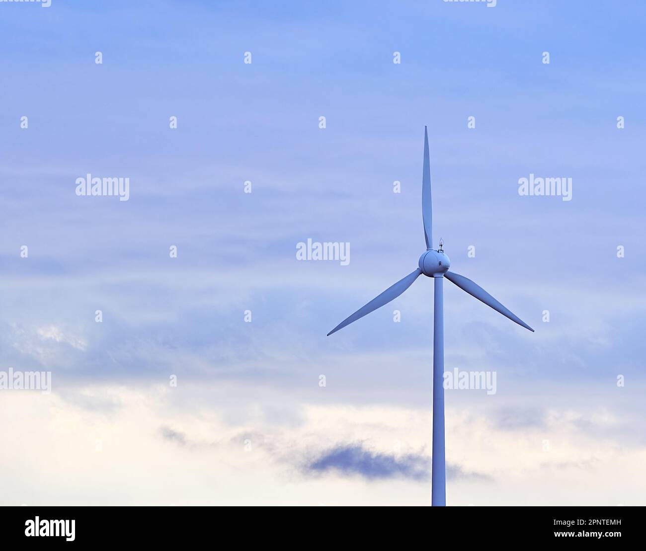 Une belle photo d'une éolienne avec des pales en rotation par jour nuageux Banque D'Images