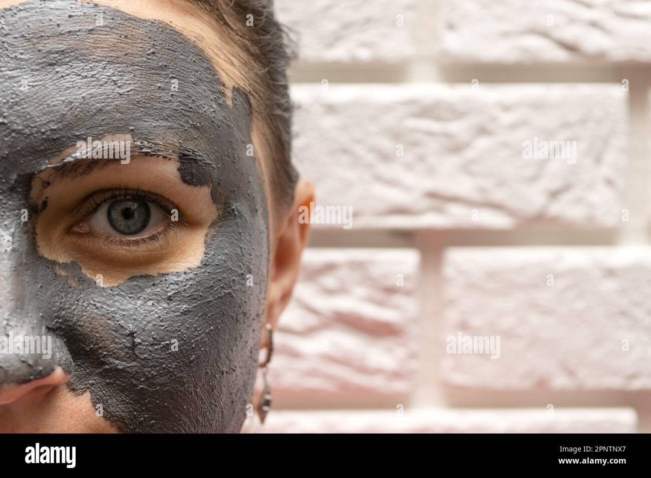 Vue à mi-hauteur du visage d'une femme avec masque cosmétique noir Banque D'Images