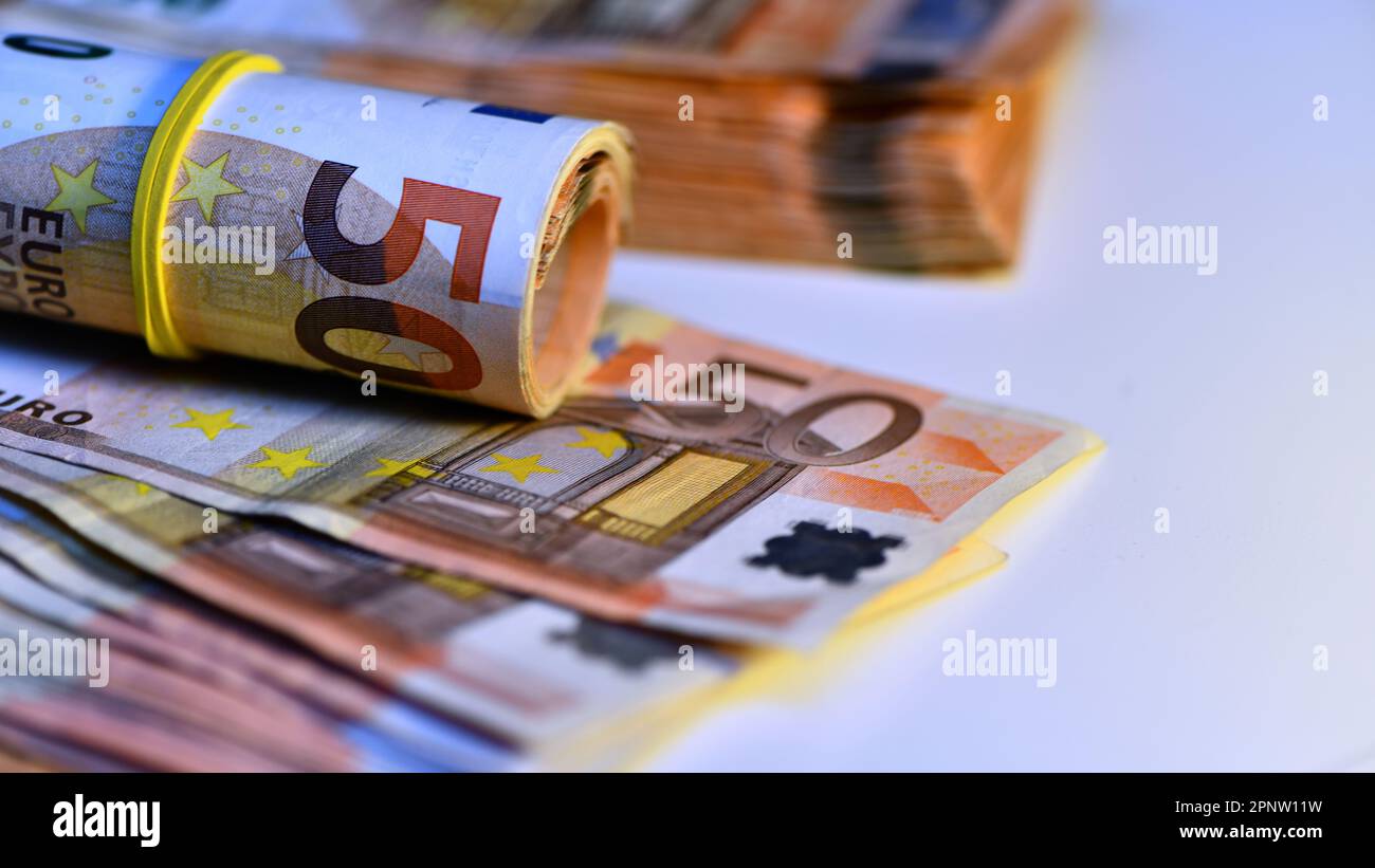 Concept de plusieurs euros : une pile de billets roulés de 50 euros reposant sur un fond blanc à hauteur de milliers d'euros en billets de 50 euros Banque D'Images