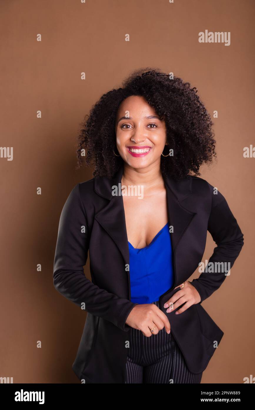 Femme de direction vêtue d'un blazer noir sur fond marron. Portrait de studio. Banque D'Images