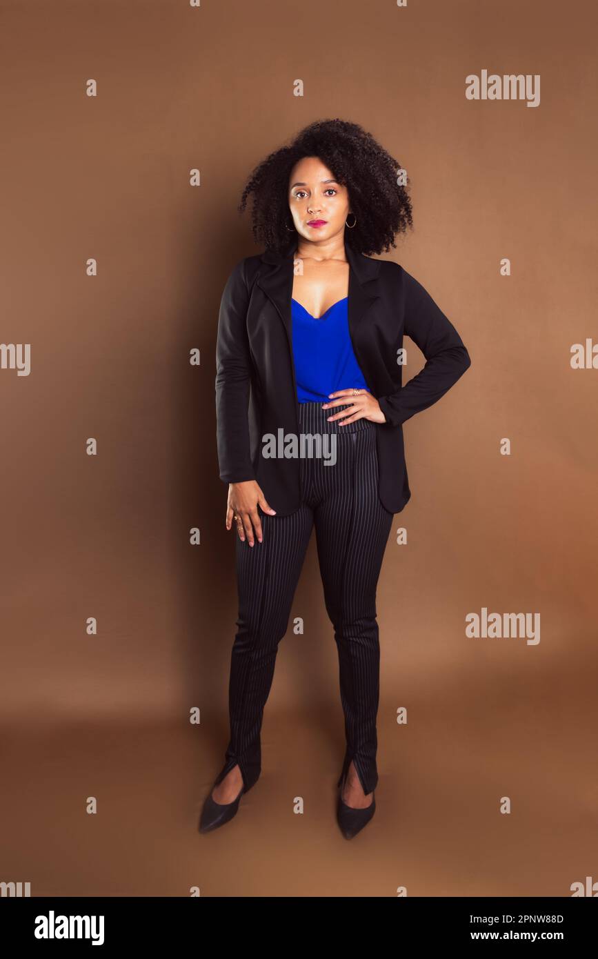 Femme de direction vêtue d'un blazer noir sur fond marron. Portrait de studio. Banque D'Images