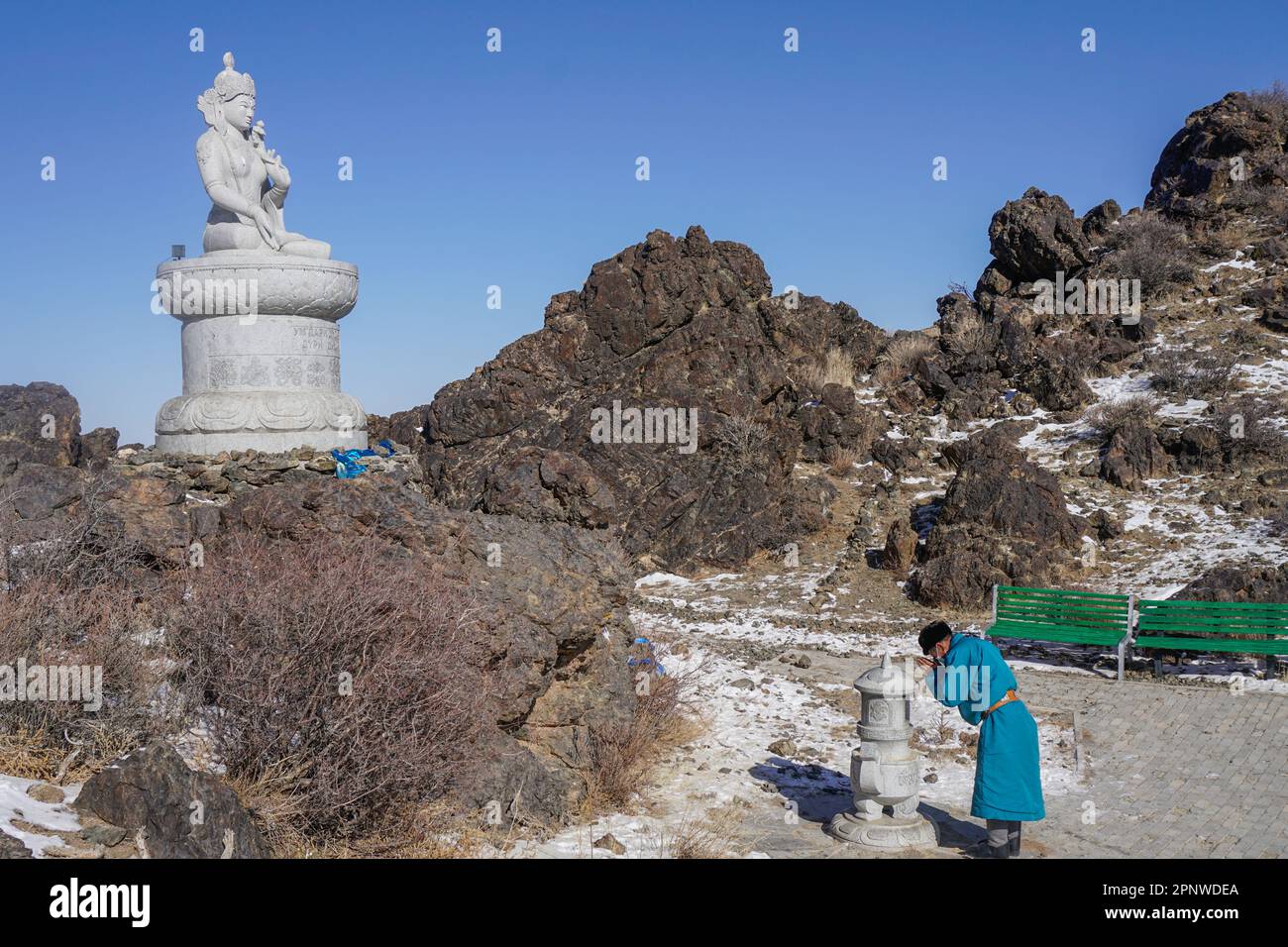 Gankhuyag Batsukh prie devant une statue de Bouddha à Khuurkhun Devseg, un monastère de Bulgan, province d'Umnugovi, Mongolie sur 9 février 2022. Selon Gankhuyag, « nous prions pour nos montagnes et nos rivières ». (Nansalmaa Oyunchimeg/Global Press Journal) Banque D'Images