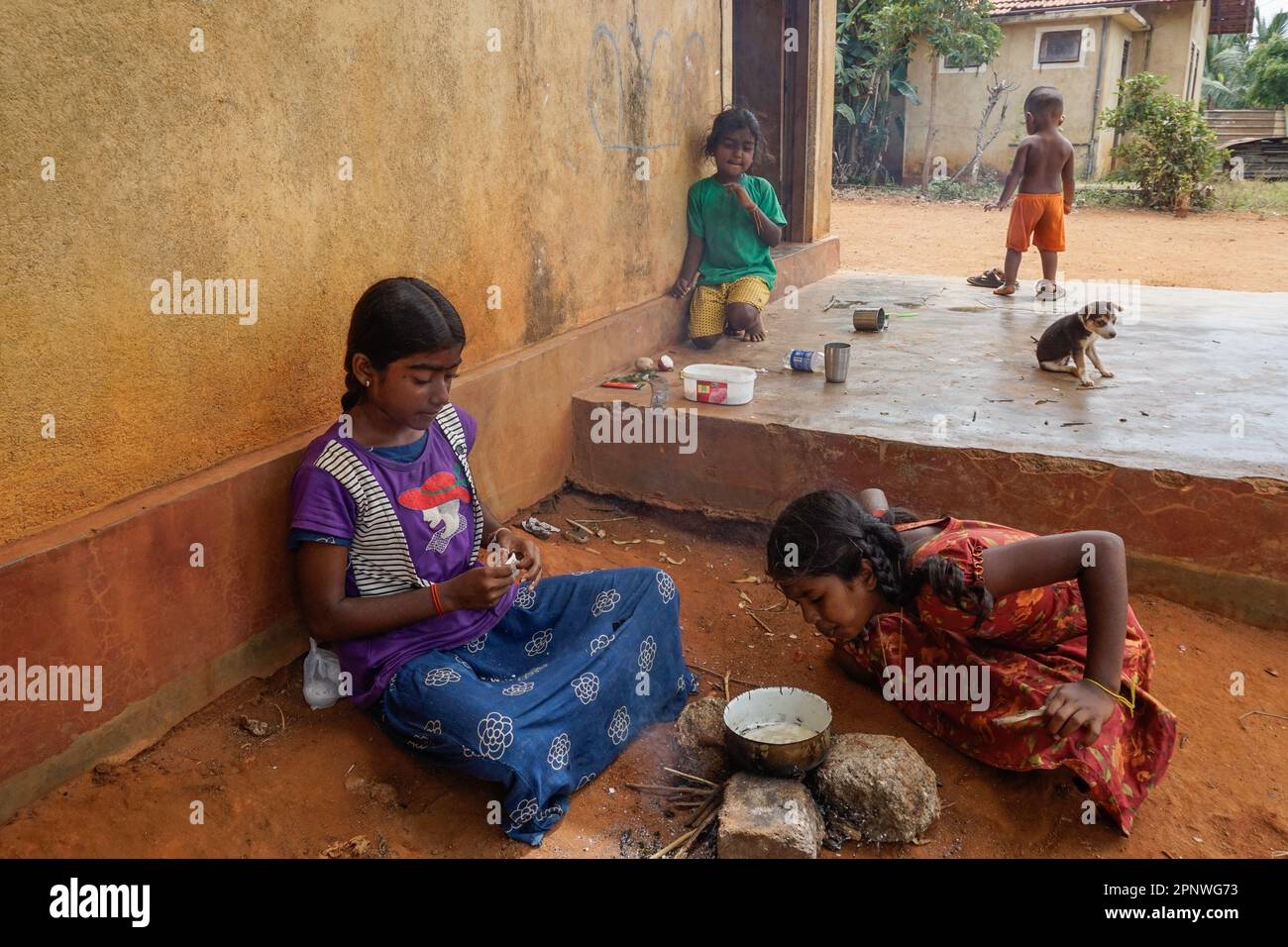 Jesunayagam Anushka, 12 ans, à gauche, et Jeyanthan Nishana, 11 ans, A droite, faire un feu pendant que Jesunayagam Powshiga, 7, montres à Jaffna, Sri Lanka sur 19 juin 2022. Pendant leurs vacances scolaires, les enfants aiment cuisiner et jouer ensemble. (Vijayatharsiny Thinesh/Global Press Journal) Banque D'Images