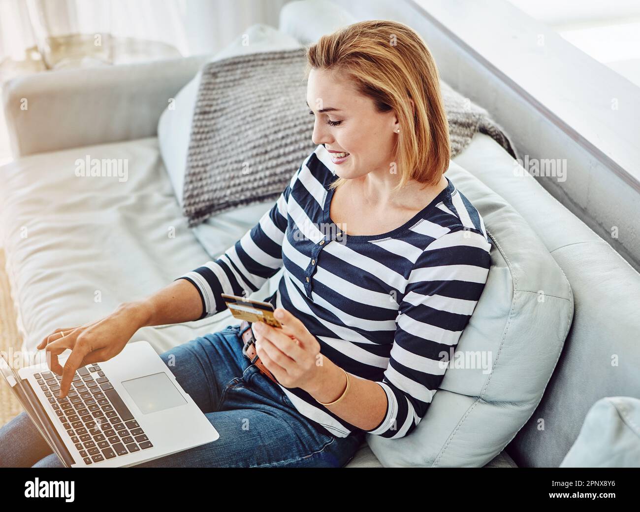 Dépenser un peu d'argent en ligne. Prise de vue en grand angle d'une jeune femme attrayante magasiner en ligne depuis le confort de la maison. Banque D'Images