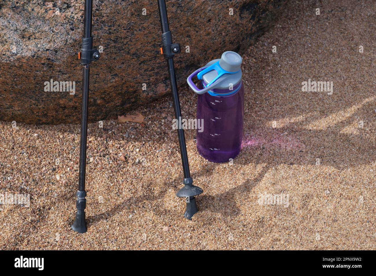 Bâtons de randonnée et bouteille d'eau dans le sable de la plage Banque D'Images