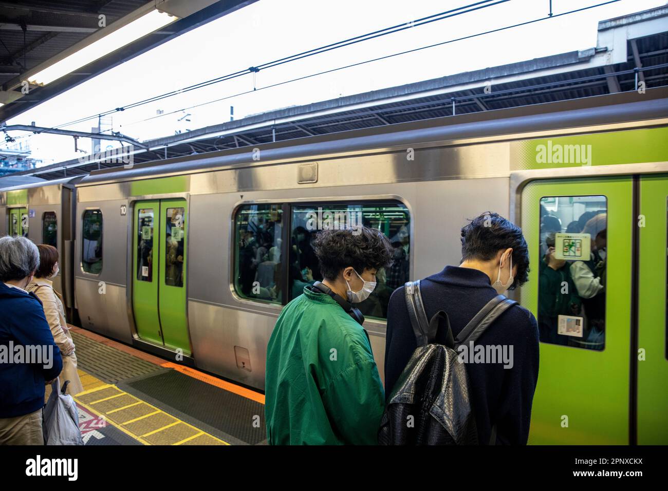 Tokyo train avril 2023 un train ferroviaire bondé arrive à la plate-forme alors que les passagers japonais attendent de monter à bord, Japan Rail, Asie Banque D'Images