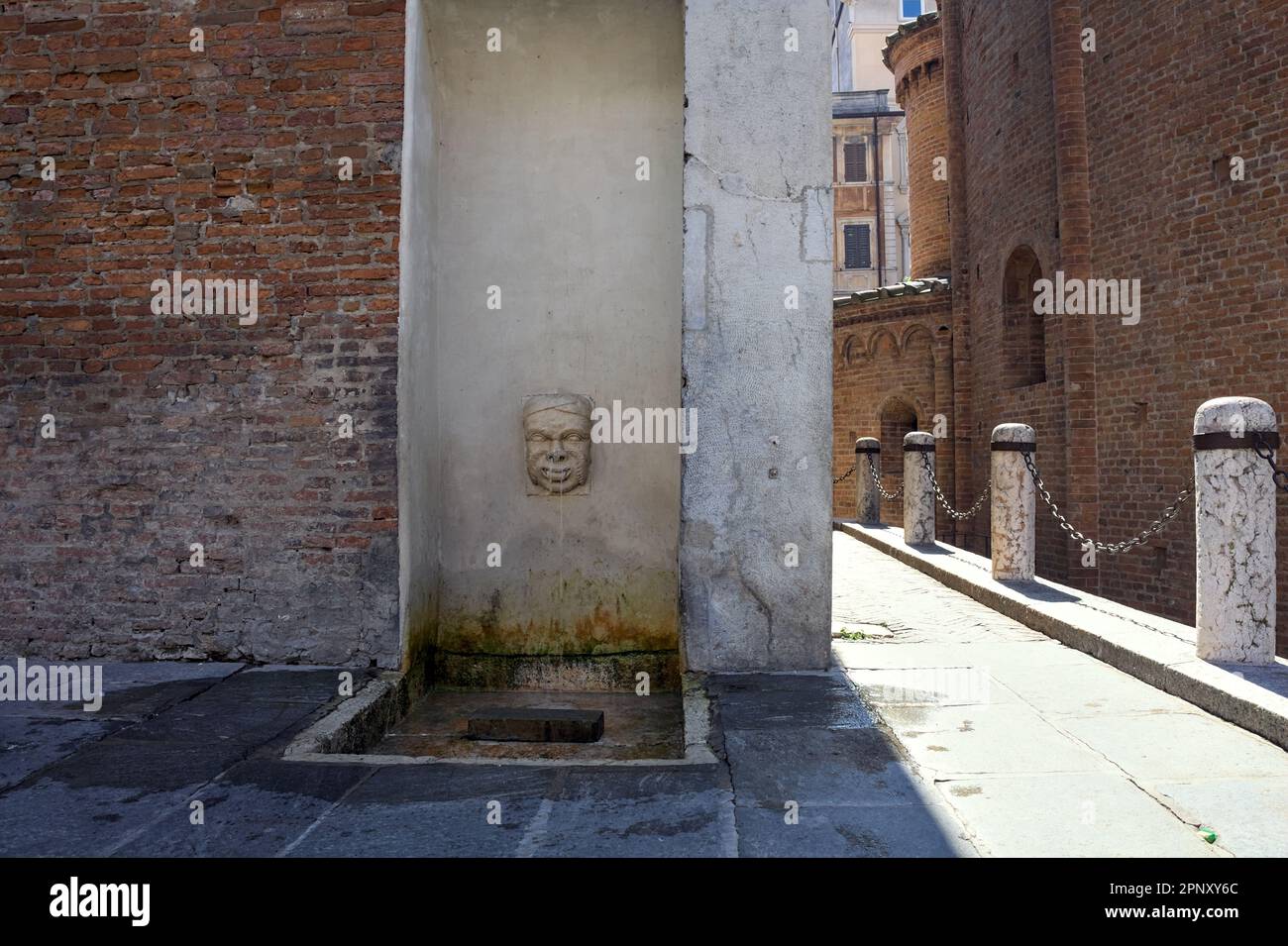 Fontaine en forme de visage dans un palais à côté d'une allée dans une ville italienne par une journée ensoleillée Banque D'Images