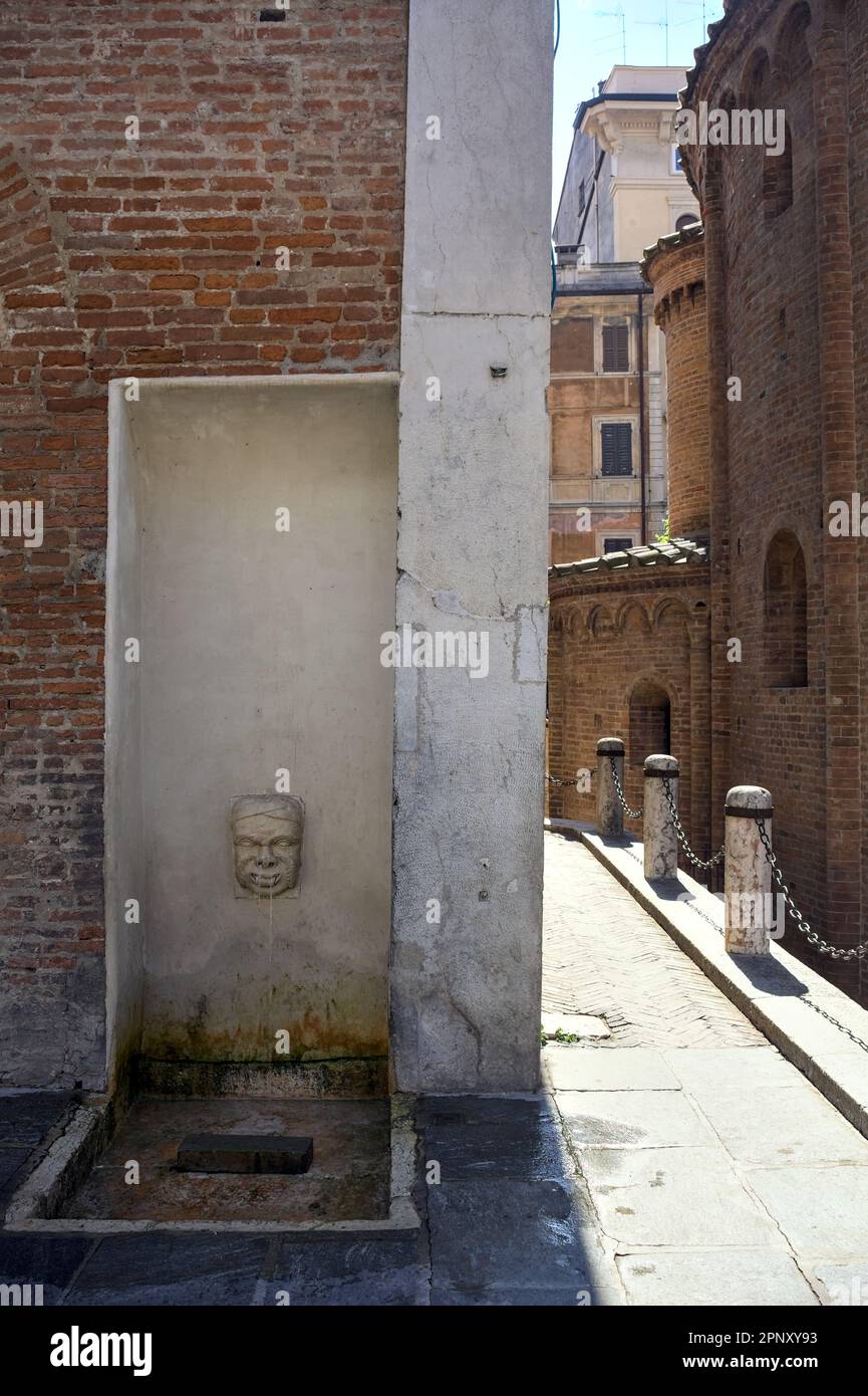 Fontaine en forme de visage dans un palais à côté d'une allée dans une ville italienne par une journée ensoleillée Banque D'Images