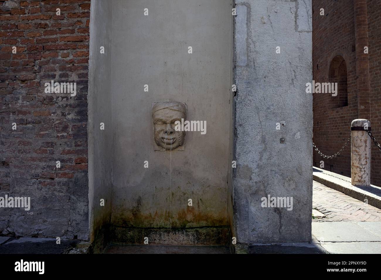 Fontaine en forme de visage dans un palais à côté d'une allée dans une ville italienne par une journée ensoleillée Banque D'Images