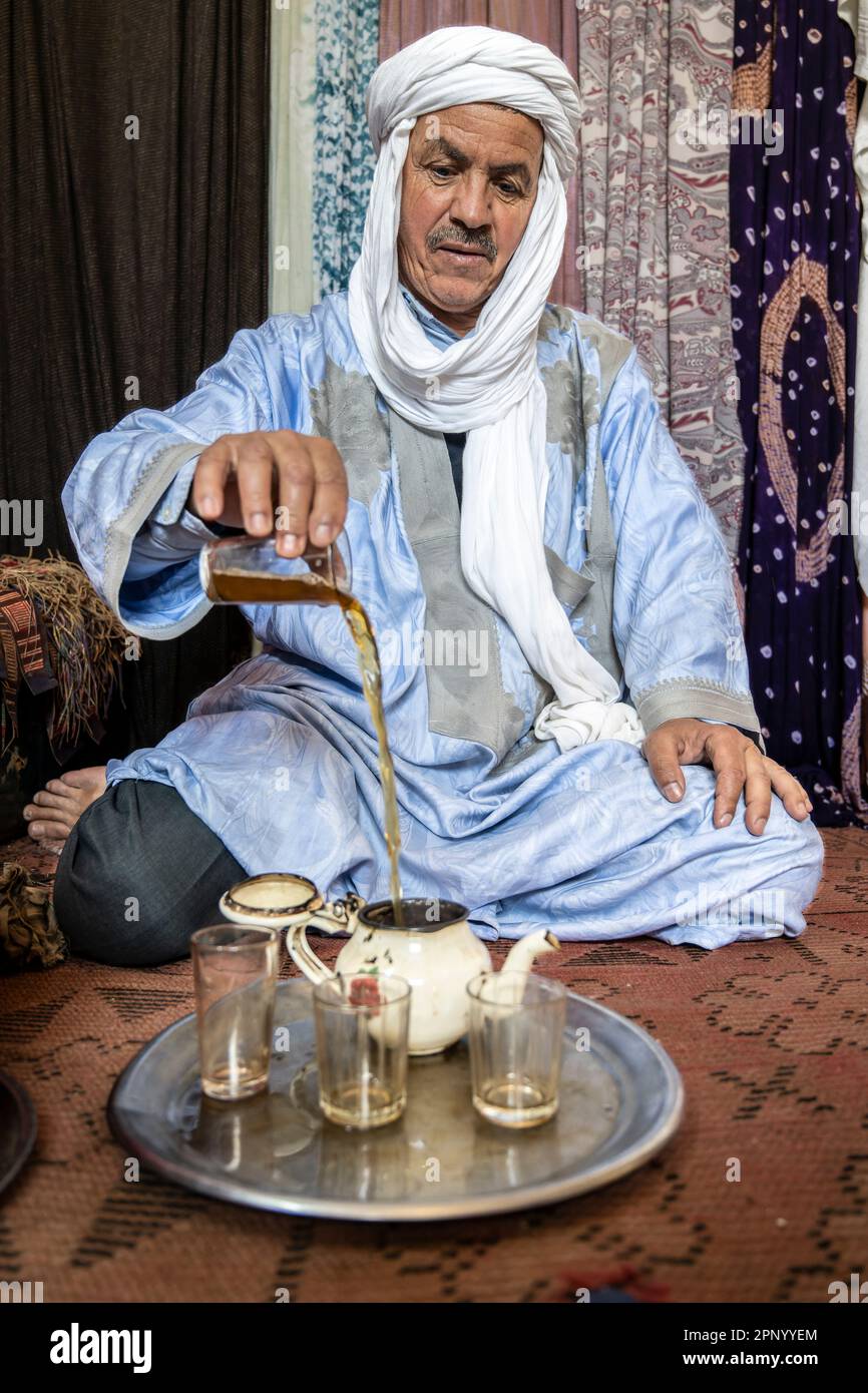 Touareg faisant du thé assis sur le sol sur un tapis. Banque D'Images