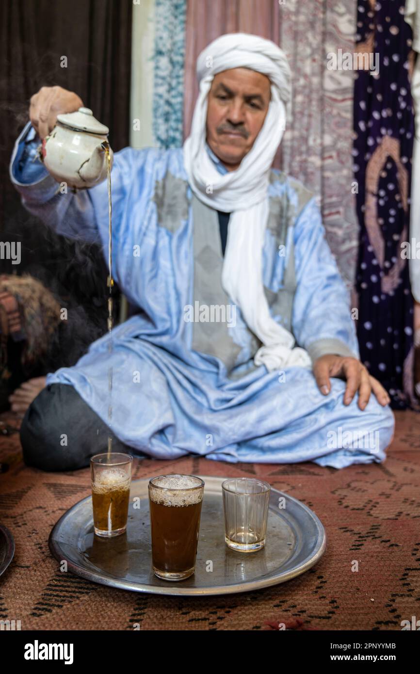 Touareg faisant du thé assis sur le sol sur un tapis. Banque D'Images