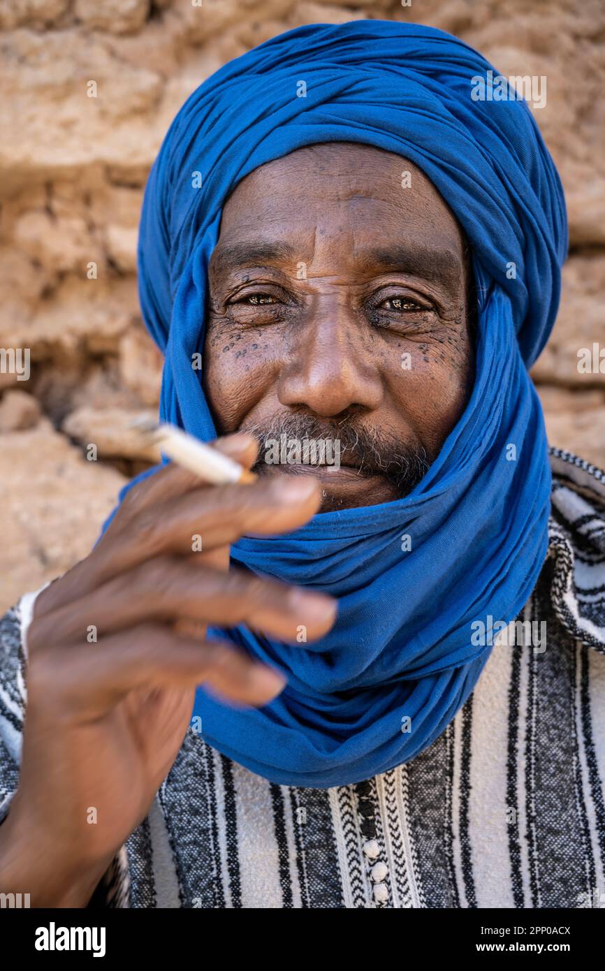 Portrait d'un homme adulte fumant vêtu de djellaba et de turban bleu. Banque D'Images