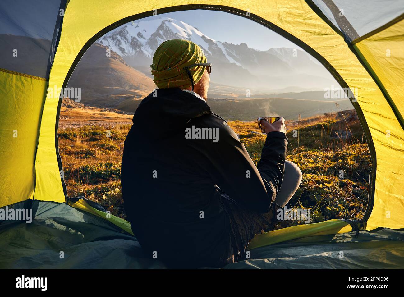 Vue de l'intérieur d'une tente de randonneur boire un thé chaud et regarder la vallée des montagnes avec le paysage de glacier de glace au coucher du soleil pendant la randonnée dans le centre de l'ASI Banque D'Images