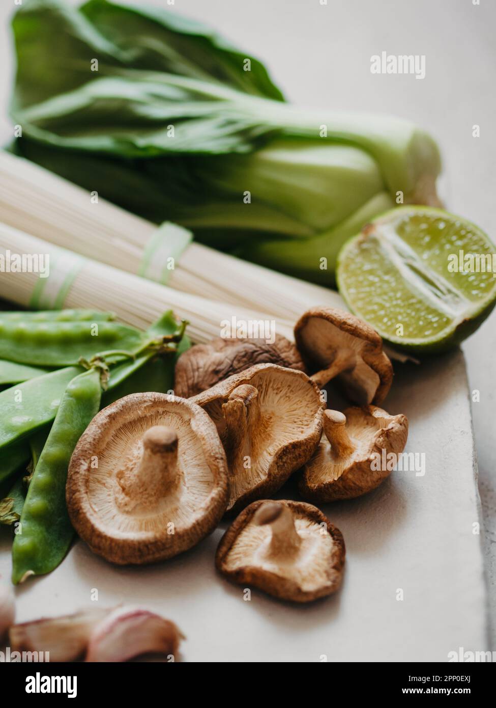 Ingrédients de cuisine pour les plats asiatiques : bok choy, champignons shiitake, soba, pois verts et ail sur l'assiette. Mise au point sélective. Vue avant. Banque D'Images