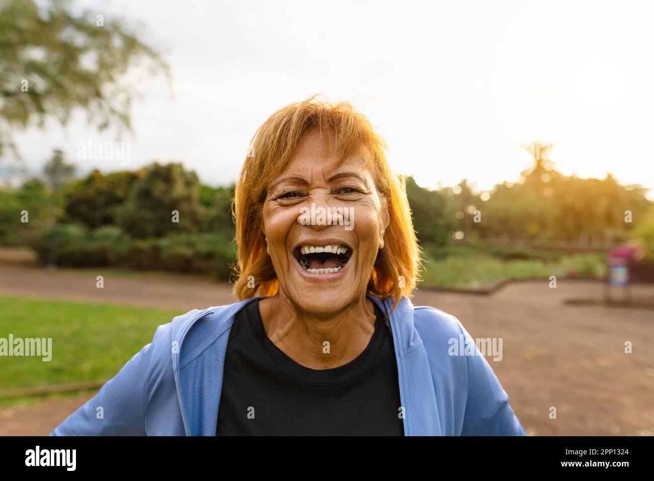 Bonne femme latine senior ayant le sourire amusant à la caméra après une activité d'entraînement dans un parc public Banque D'Images