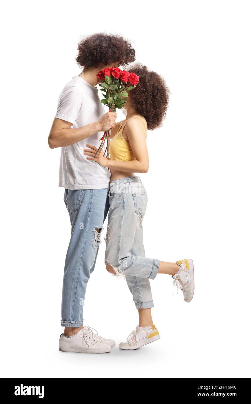 Prise de vue en longueur de jeunes couples embrassant et cachant behinf un bouquet de roses rouges isolées sur fond blanc Banque D'Images