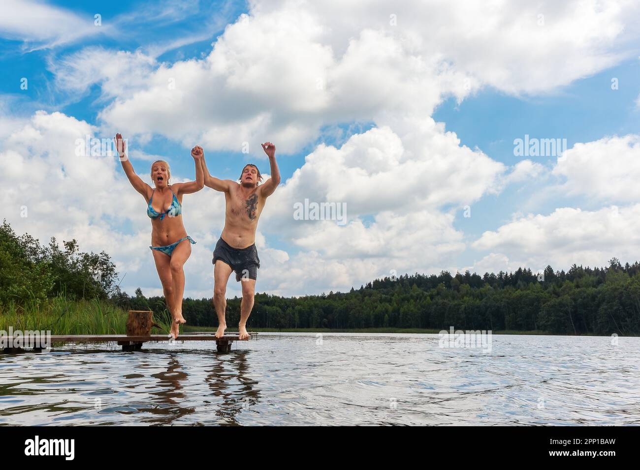 Un couple homme et femme sautant dans l'eau du lac. Vacances d'été dans la nature Banque D'Images
