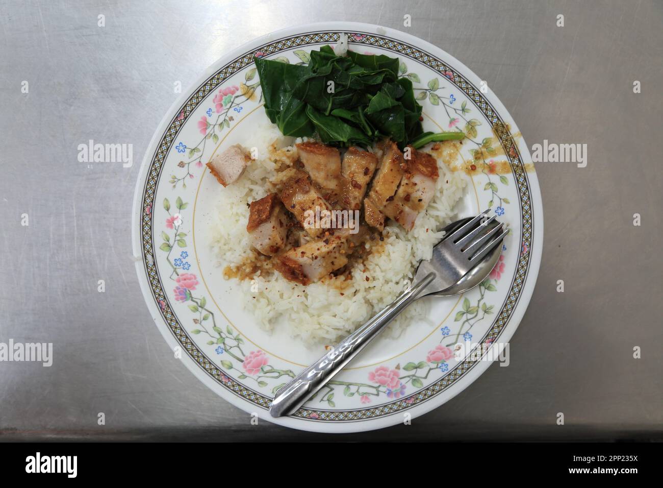 Une assiette de cuisine d'inspiration asiatique avec une portion de porc chinois tendre et croustillant servie avec un côté de riz vapeur Banque D'Images