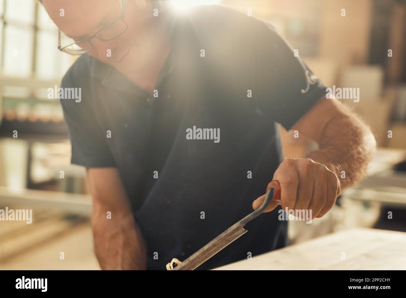 Le menuisier utilise un outil de coupe manuel pour chanfreiner et sculpter les bords, en éliminant sans à-coups les boucles et les copeaux de manière régulière ou irrégulière Banque D'Images