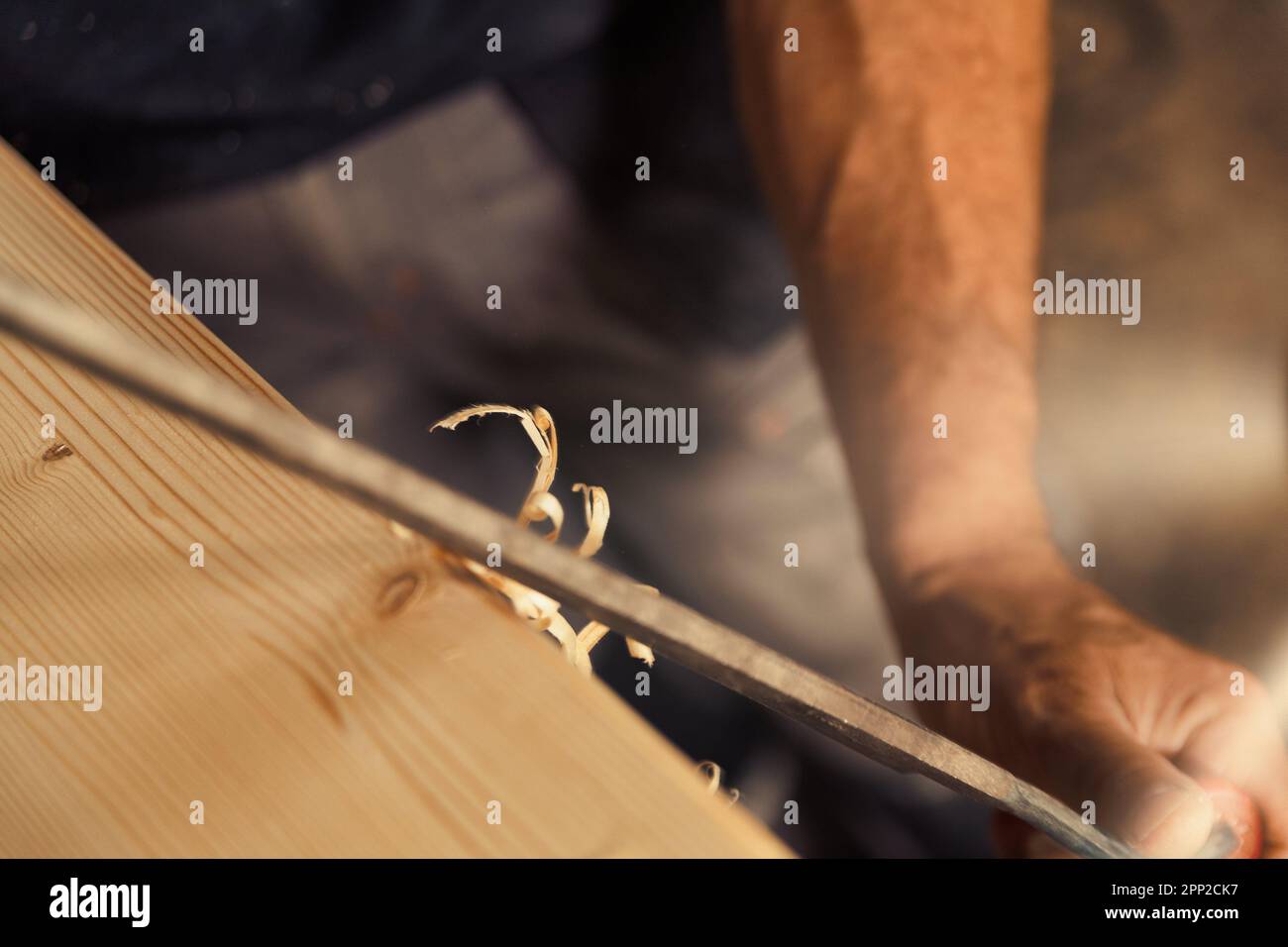 Le menuisier utilise un outil de coupe manuel pour chanfreiner et sculpter les bords, en éliminant sans à-coups les boucles et les copeaux de manière régulière ou irrégulière Banque D'Images
