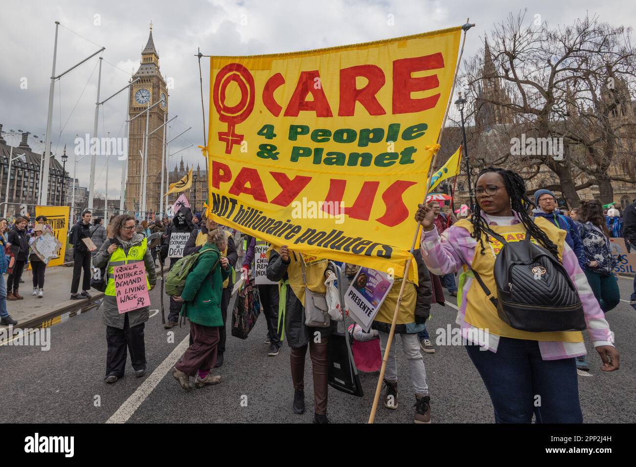 Londres, Royaume-Uni. 21 avril 2023. Les manifestants de extinction Rebellion et des groupes alliés défilent près de Big Ben, exigeant la justice climatique, des salaires équitables pour les travailleurs sociaux et une action contre les pollueurs milliardaires. Une bannière jaune proéminente indique « CARE 4 People & Planet – PAY US NOT milliardaire Polonais », avec un symbole féministe du poing levé. La manifestation met en avant un activisme intersectionnel liant les préoccupations de genre, de travail et d'environnement. Les militants de extinction Rebellion organisent une manifestation de quatre jours dans divers endroits du centre de Londres. L'événement est nommé le Big One. Penelope Barritt/Alamy Live News Banque D'Images