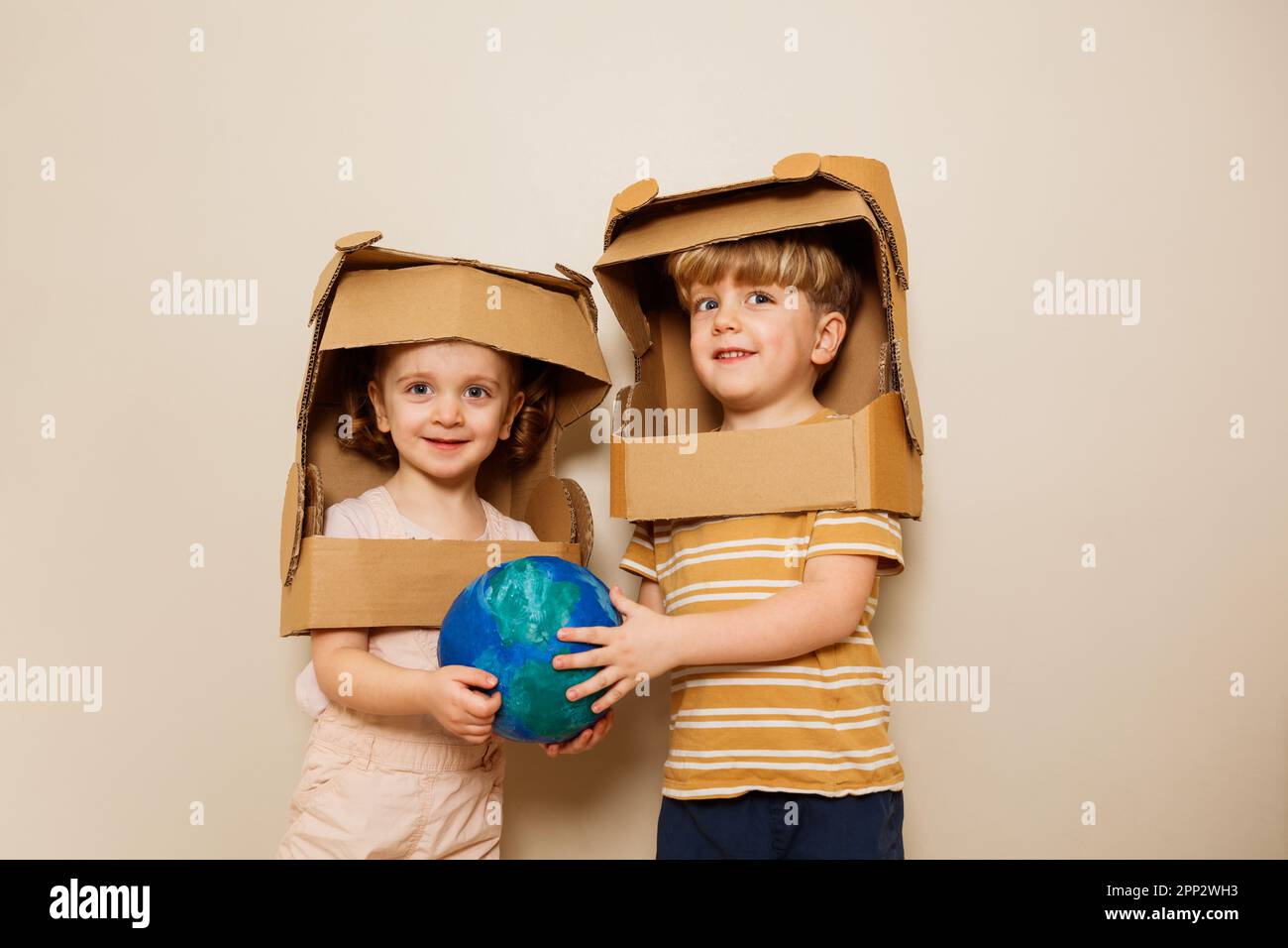 Garçon et fille avec la planète Terre dans les mains portent un casque d'astronaute Banque D'Images