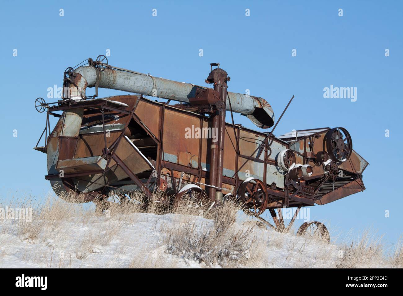 Une machine de battage ancienne abandonnée ressemble à un lézard métallique sur une pente enneigée dans les plaines du Montana Banque D'Images