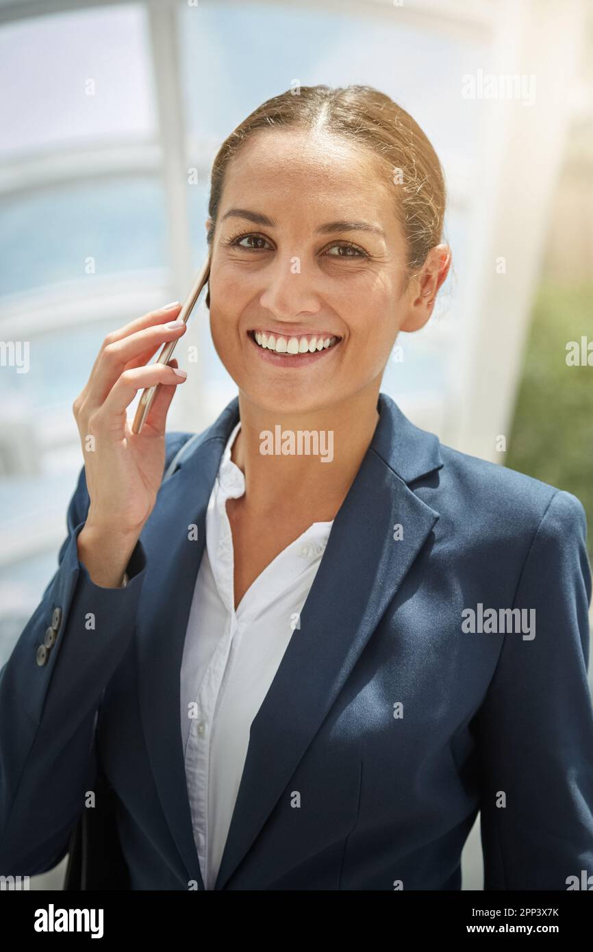 La réussite lui fait sourire. Portrait d'une jeune femme d'affaires parlant sur son téléphone portable en route vers le bureau. Banque D'Images